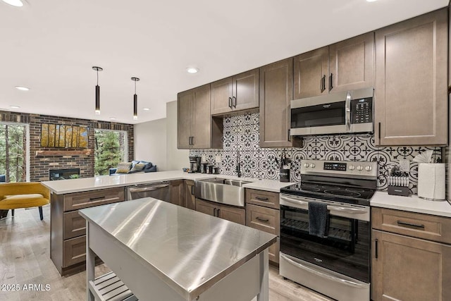 301 S O Leary St, Flagstaff, AZ 86001 - kitchen featuring tasteful backsplash, a peninsula, stainless steel appliances, a brick fireplace, and a sink
