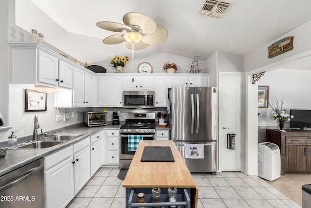 863 W 14th Ave, Apache Junction, AZ 85120 - kitchen with stainless steel appliances, vaulted ceiling, white cabinetry, wood counters, and light tile patterned flooring