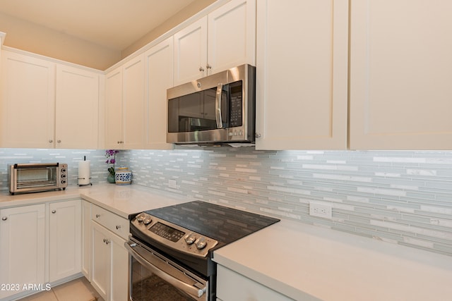 kitchen featuring appliances with stainless steel finishes, tasteful backsplash, light tile patterned floors, and white cabinets