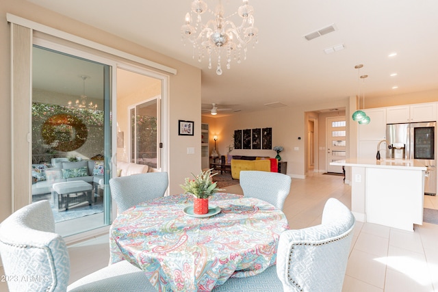 tiled dining space featuring ceiling fan with notable chandelier and sink