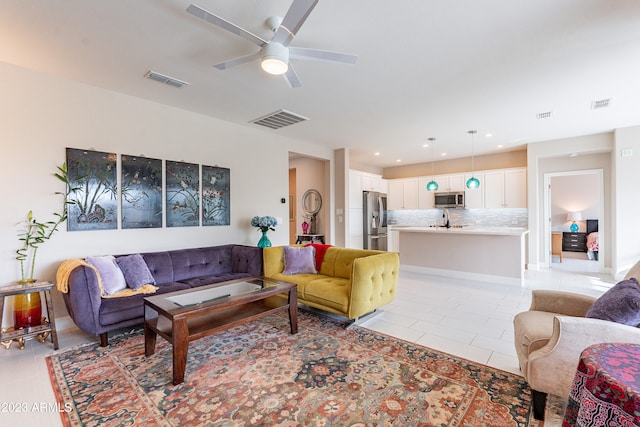 tiled living room featuring ceiling fan and sink