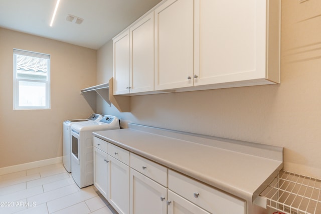 laundry room featuring washer and clothes dryer, cabinets, and light tile patterned floors