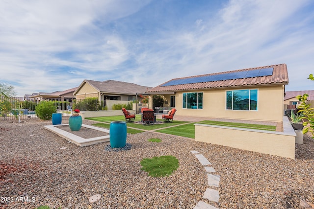 rear view of property with an outdoor living space, solar panels, and a patio