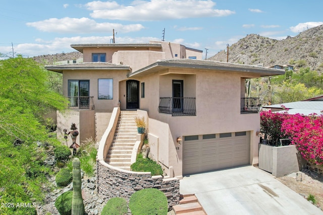 view of front of property with a garage, a balcony, stairs, concrete driveway, and stucco siding