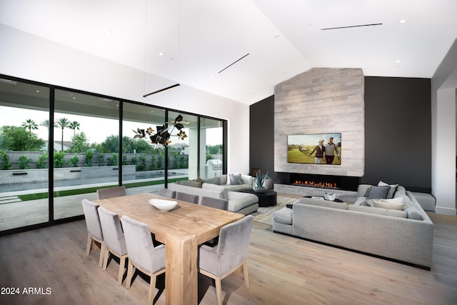 dining area featuring hardwood / wood-style floors, lofted ceiling, and a large fireplace