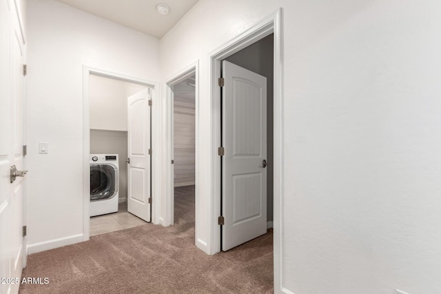 corridor featuring washer / dryer and light carpet