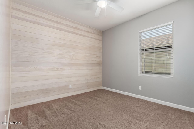 unfurnished room featuring ceiling fan, carpet, and wood walls