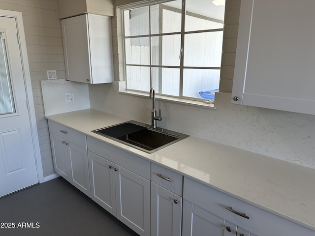 kitchen with light stone counters, sink, decorative backsplash, and white cabinets