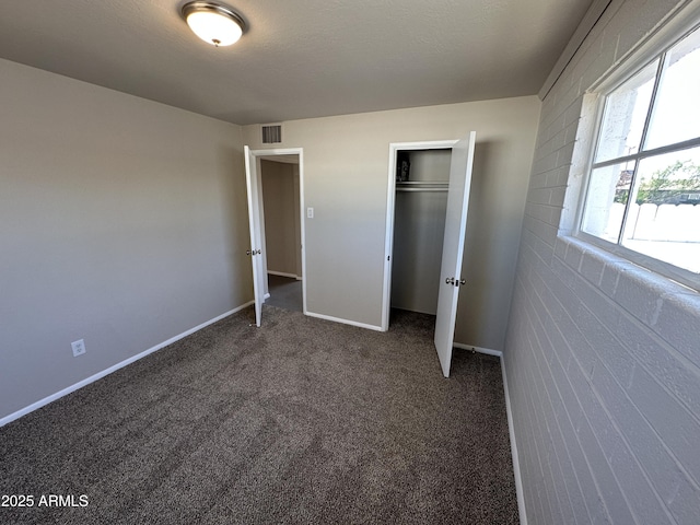 unfurnished bedroom with dark colored carpet, a textured ceiling, and a closet