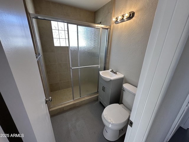 bathroom featuring vanity, a shower with door, and toilet