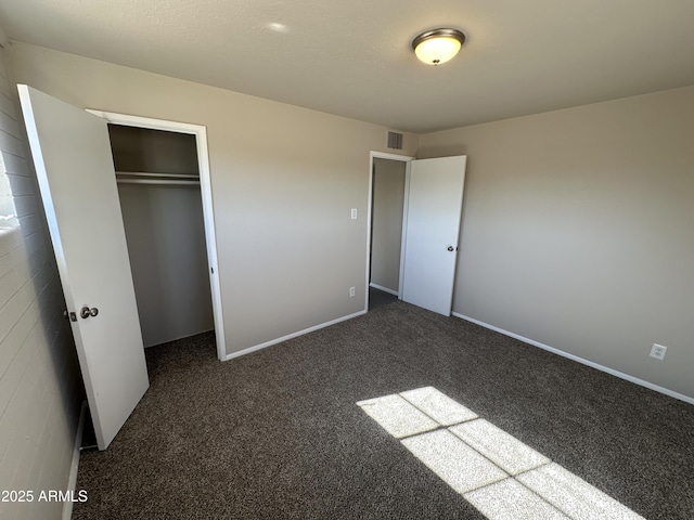 unfurnished bedroom featuring dark carpet and a closet