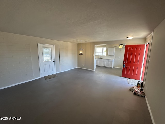 foyer featuring ceiling fan, brick wall, sink, and a textured ceiling