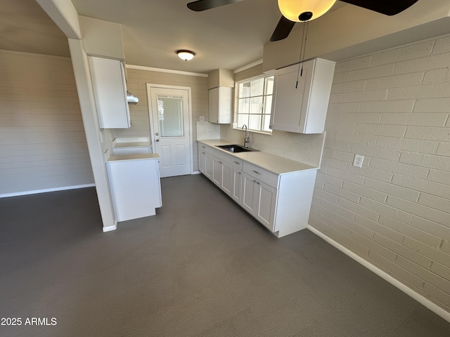 kitchen with white cabinetry, sink, ceiling fan, and brick wall