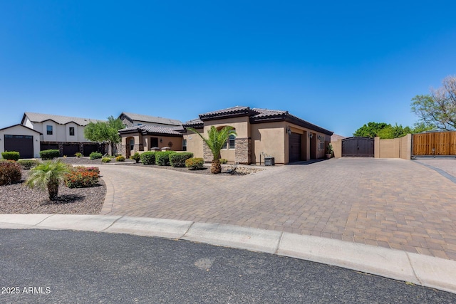 view of front facade with decorative driveway, a tile roof, a gate, and stucco siding