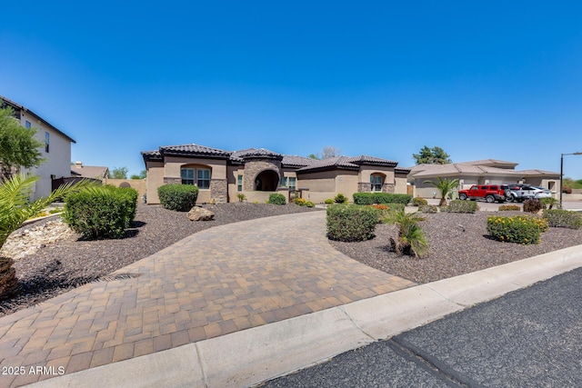 mediterranean / spanish home with stucco siding, a tile roof, and fence