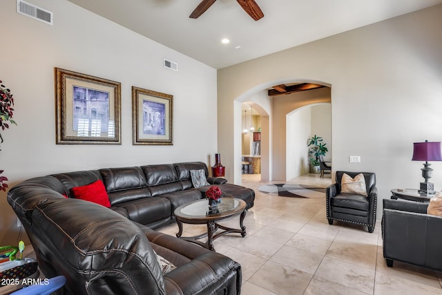 living room featuring light tile patterned floors, arched walkways, ceiling fan, and visible vents