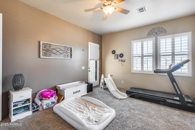 exercise room with carpet floors, a ceiling fan, and visible vents