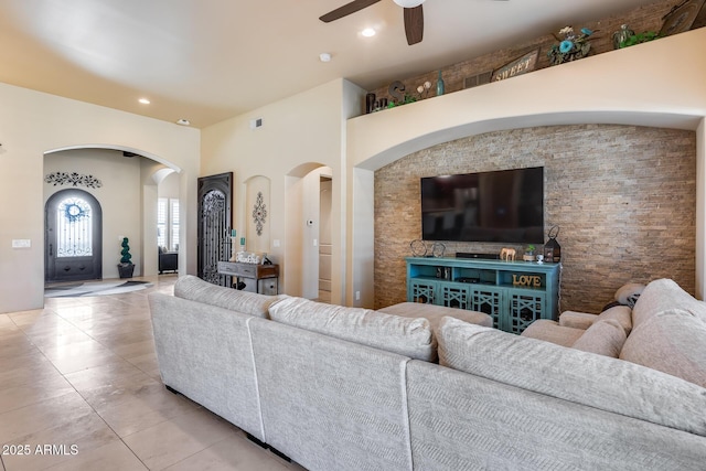 living room featuring a ceiling fan, visible vents, arched walkways, recessed lighting, and light tile patterned flooring