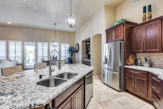 kitchen with light stone countertops, a sink, tasteful backsplash, stainless steel refrigerator with ice dispenser, and dishwashing machine