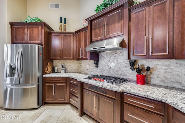 kitchen with backsplash, visible vents, appliances with stainless steel finishes, light stone countertops, and under cabinet range hood