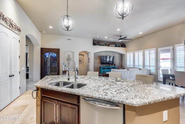 kitchen with a sink, dishwasher, arched walkways, an island with sink, and a ceiling fan