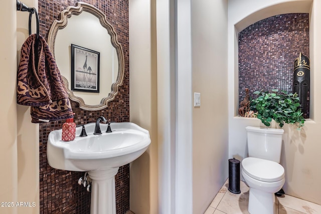 half bathroom featuring tile patterned flooring, toilet, and tasteful backsplash