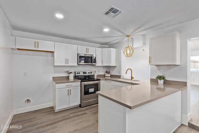 kitchen featuring kitchen peninsula, decorative light fixtures, appliances with stainless steel finishes, light hardwood / wood-style floors, and sink