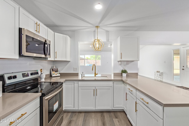 kitchen featuring decorative light fixtures, stainless steel appliances, white cabinets, sink, and light wood-type flooring