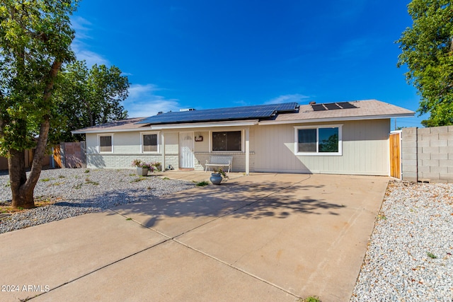 ranch-style home with solar panels and a patio area