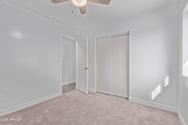 unfurnished bedroom with light colored carpet, a closet, and ceiling fan