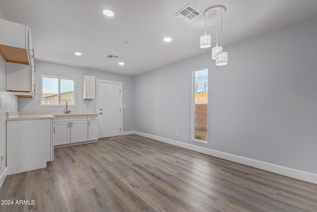 kitchen featuring white cabinets, sink, light hardwood / wood-style floors, and decorative light fixtures