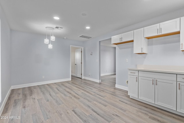 kitchen with hanging light fixtures, light wood-type flooring, and white cabinetry