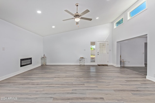 unfurnished living room with hardwood / wood-style flooring, ceiling fan, and high vaulted ceiling