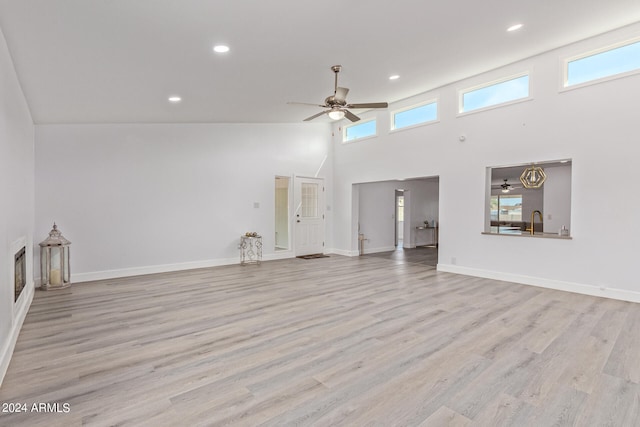 unfurnished living room with high vaulted ceiling, light hardwood / wood-style floors, and ceiling fan