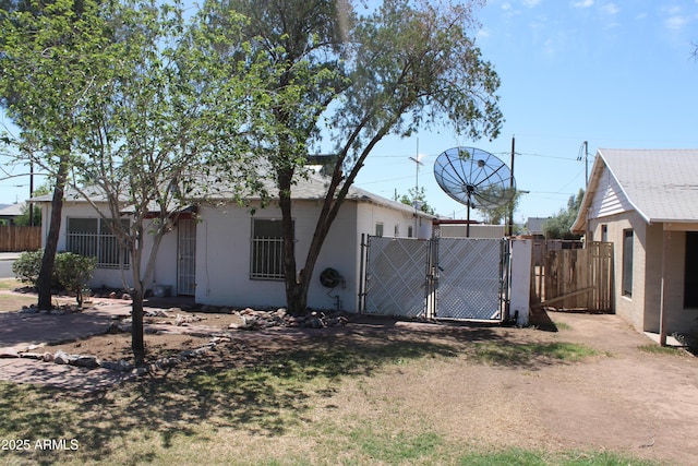 exterior space with stucco siding, a gate, and fence