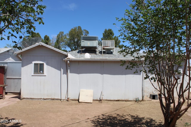 back of house featuring a shingled roof and cooling unit
