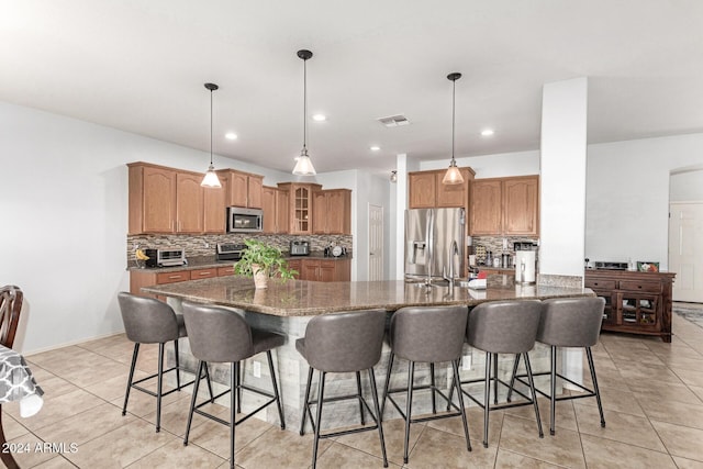 kitchen with a kitchen breakfast bar, decorative light fixtures, backsplash, and appliances with stainless steel finishes