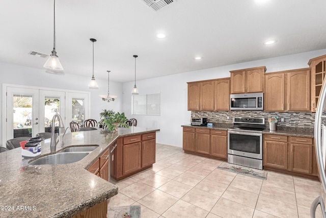 kitchen featuring french doors, backsplash, stainless steel appliances, sink, and pendant lighting