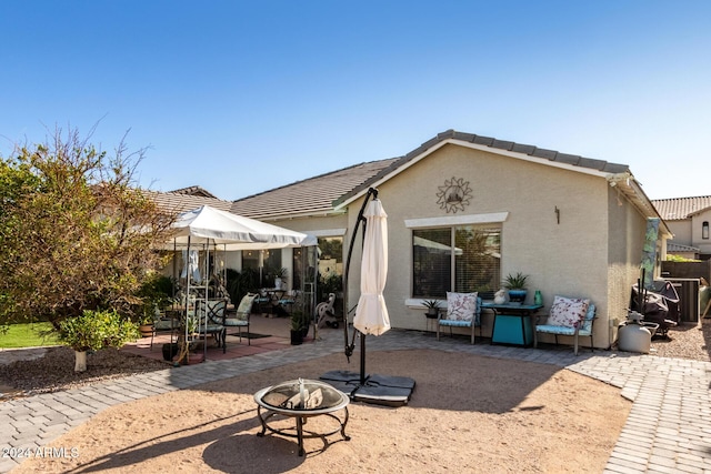 back of property with a fire pit and a patio area