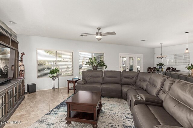 tiled living room with ceiling fan with notable chandelier