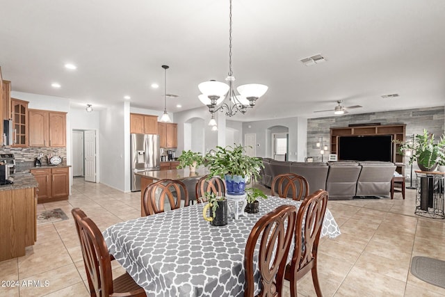 dining space with light tile patterned floors and ceiling fan with notable chandelier