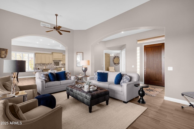 living room featuring light wood finished floors, baseboards, visible vents, and a ceiling fan