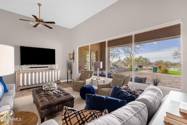 living room featuring baseboards, a ceiling fan, vaulted ceiling, and wood finished floors