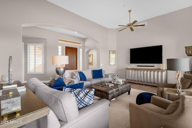 living area featuring arched walkways, ceiling fan, baseboards, and wood finished floors