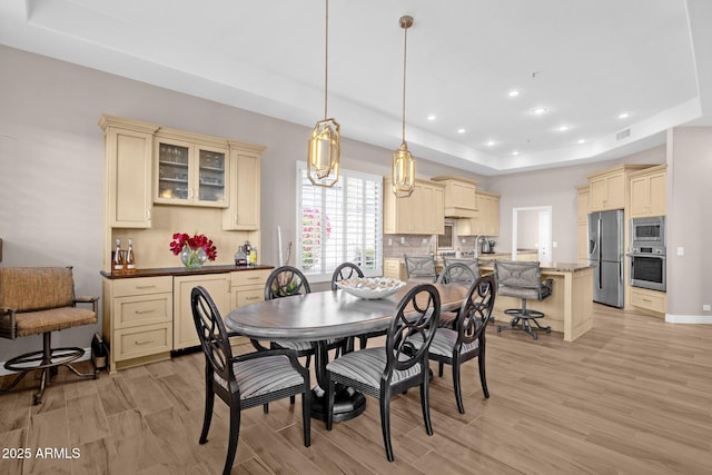 dining room with light wood-style flooring, visible vents, a tray ceiling, and recessed lighting