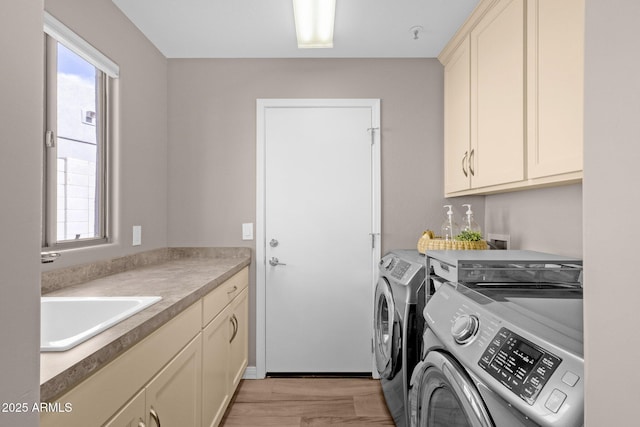 laundry area featuring light wood-style floors, a wealth of natural light, cabinet space, and separate washer and dryer