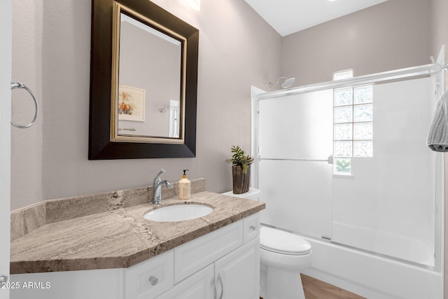 bathroom with combined bath / shower with glass door, vanity, and toilet