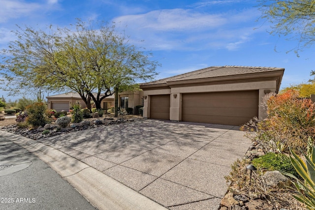 view of front facade featuring an attached garage, a tile roof, concrete driveway, and stucco siding