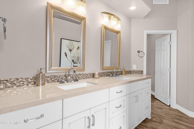 full bathroom featuring double vanity, wood finished floors, a sink, and visible vents