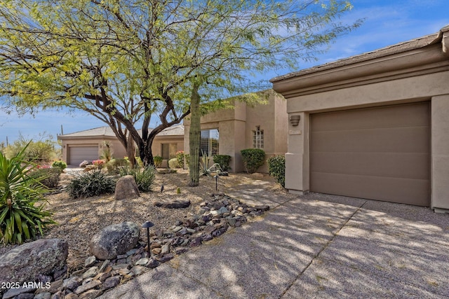 adobe home with a garage, driveway, and stucco siding